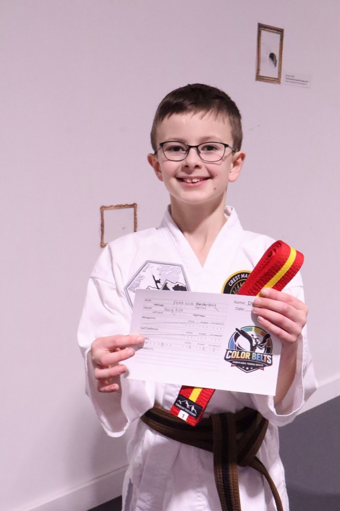 Karate Kids student proudly holding his belt test scorecard