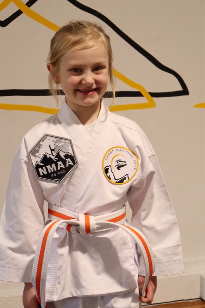 Smiling Little Dragons student in her orange belt uniform